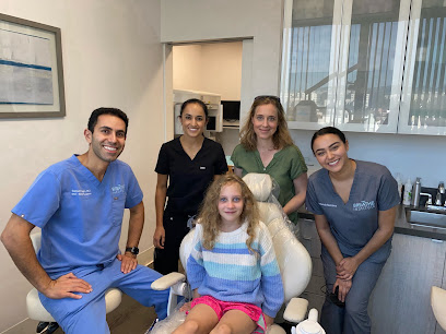 Four members of the Wray Family Dental team smiling with a young patient seated in a treatment room